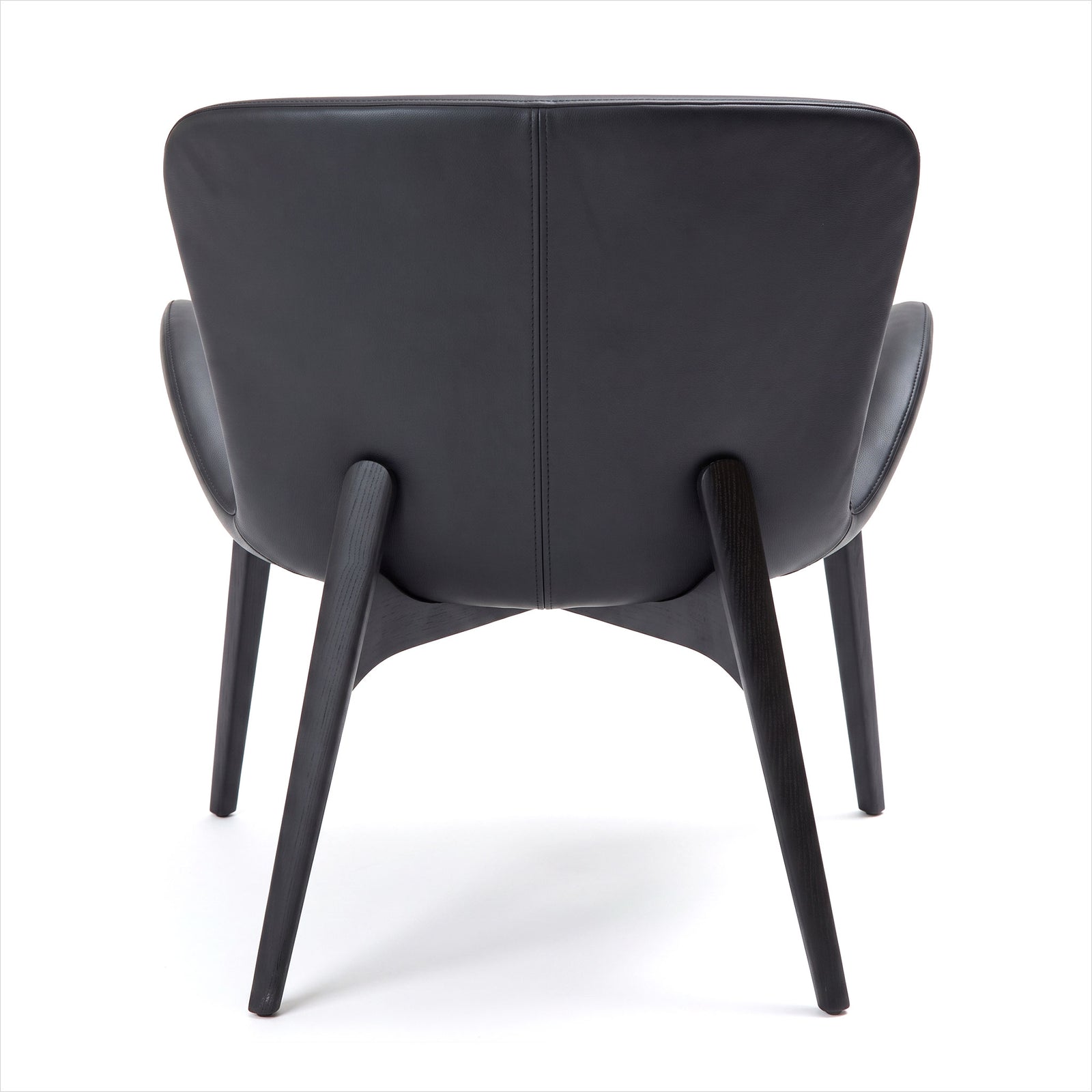 A modern black leather armchair shown from the back, featuring a curved backrest, integrated side bolsters, and tapered wooden legs on a white background.