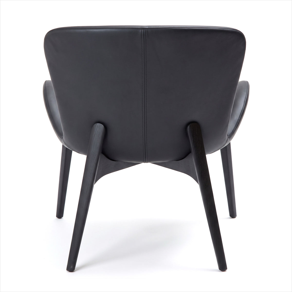 A modern black leather armchair shown from the back, featuring a curved backrest, integrated side bolsters, and tapered wooden legs on a white background.